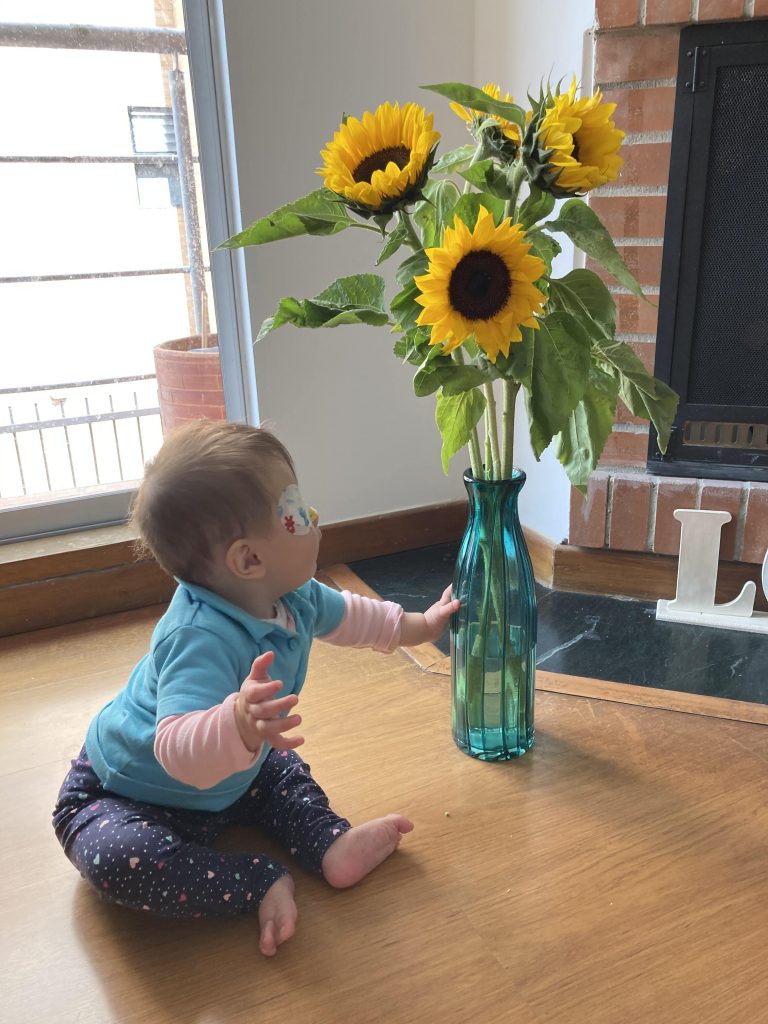 Parche en ojo de bebe jugando con la flore